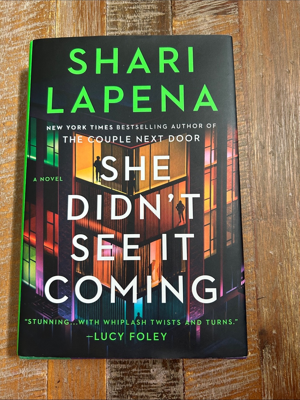 She Didn't See It Coming by Shari Lapena - Black Cover with Neon Accent